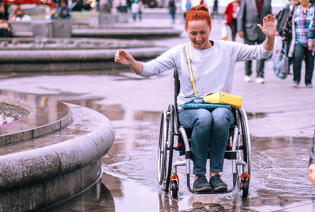 BetterDry Day adult briefs give you medium protection so you can have confidence to live your best life! Here a woman in a wheelchair is happily wheeling through a puddle.